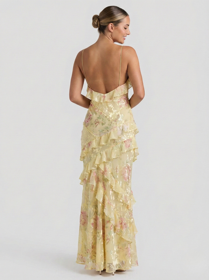 Back view of women's yellow and pink floral maxi dress featuring open back and ruffled detailing.