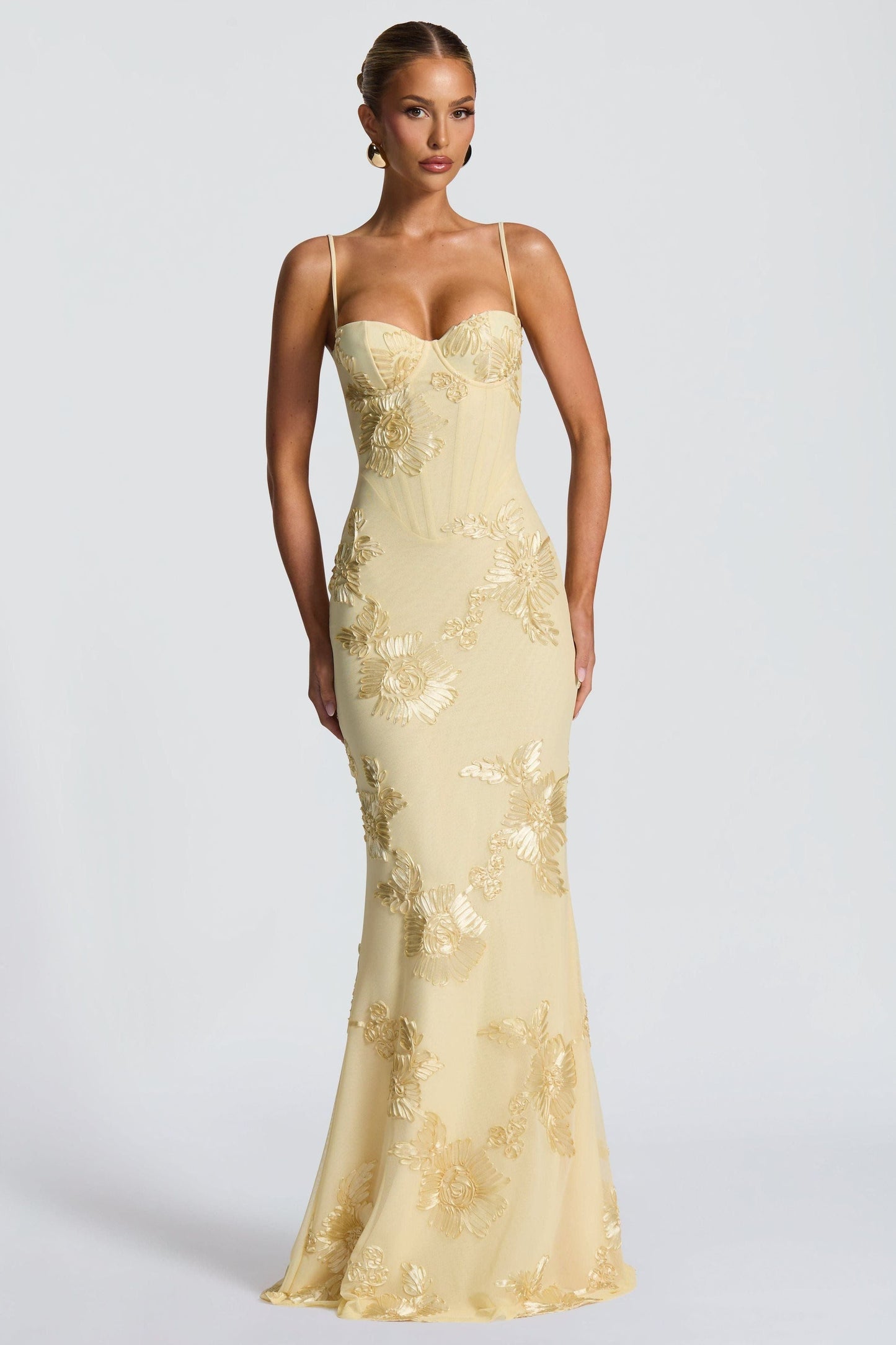 Close-up of the bodice and waist of a light yellow floral sweetheart maxi dress, showing embroidered details and corset-style stitching.