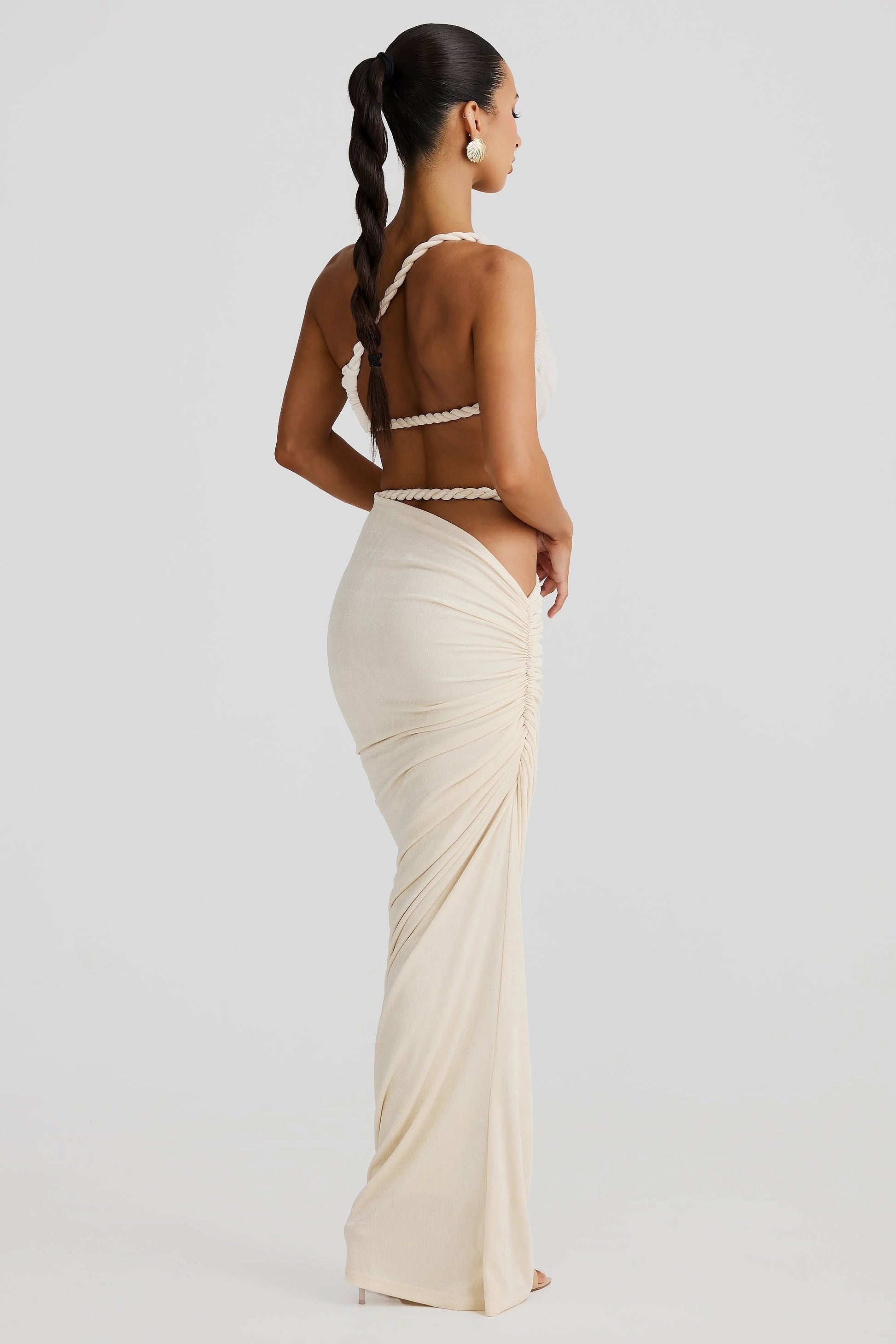 Back view of a women's cream ruched cut out maxi 2 piece set, showing braided rope straps and ruched skirt.