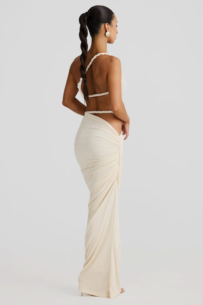 Back view of a women's cream ruched cut out maxi 2 piece set, showing braided rope straps and ruched skirt.