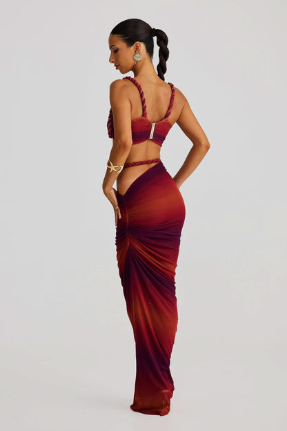 Back view of a women's ombre red and burgundy ruched cut out maxi 2 piece set with braided rope details.
