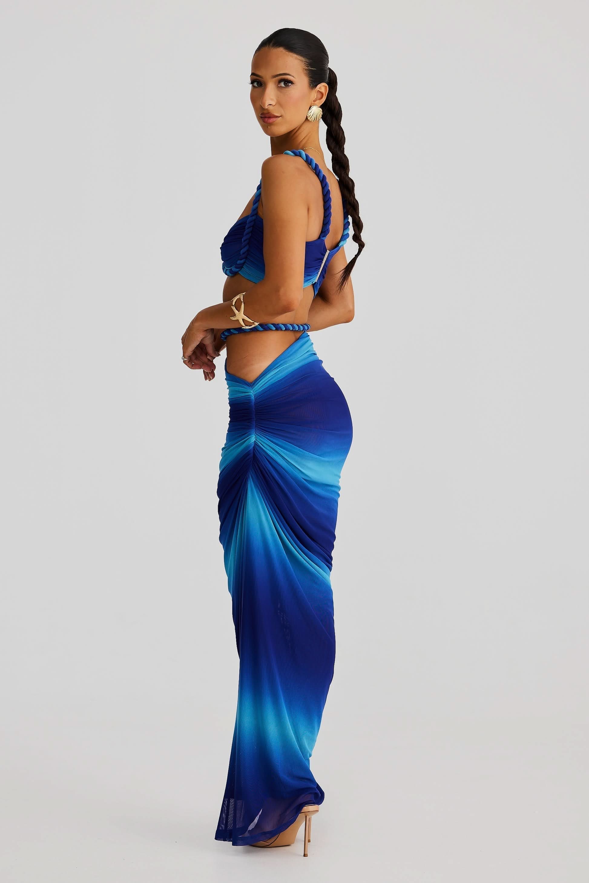 Side view of a women's ombre blue ruched cut out maxi 2 piece set, showcasing the braided rope straps.