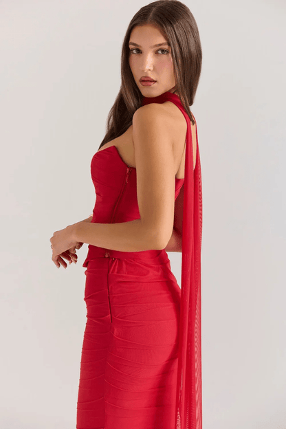 Close-up side view of the Hailey red dress, showing the texture of the ruched mesh, the structured corset bodice, and the choker scarf drape.
