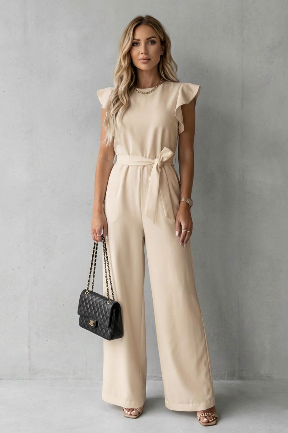 Front view of a nude-colored ruffle sleeve wide leg jumpsuit with a tied belt, suitable for various events.
