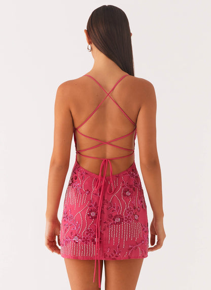 Back view of a fuchsia sequin mini party dress, featuring criss-cross back straps and a tie-up detail.