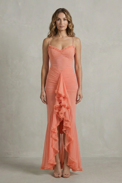 Full-length front view of a woman wearing a coral sleeveless ruched ruffle maxi dress, ideal as a midi wedding guest dress.
