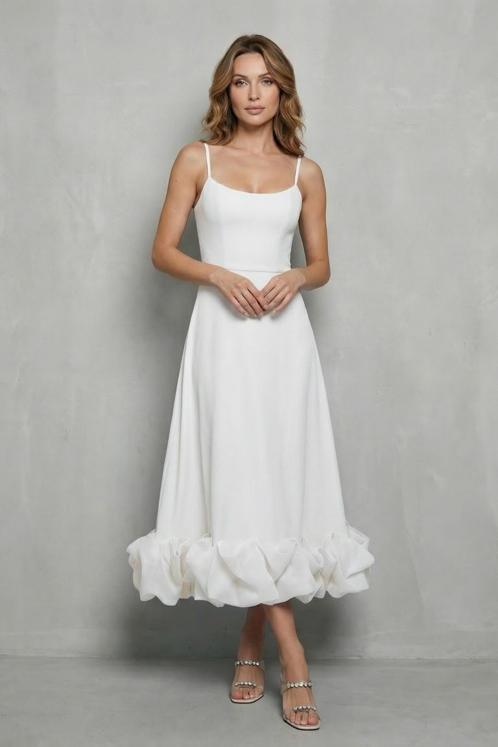 Full-length view of a woman wearing a white sleeveless midi dress with a ruffled hem, perfect for vacation dresses or a white silk dress.
