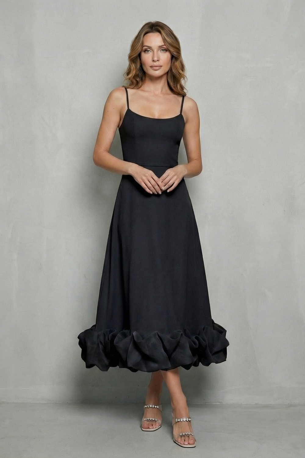 Woman posing in a black sleeveless midi dress with a full ruffled hem, a versatile midi dress for women or womens wedding guest dresses.