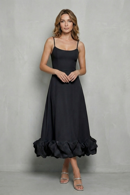 Woman posing in a black sleeveless midi dress with a full ruffled hem, a versatile midi dress for women or womens wedding guest dresses.