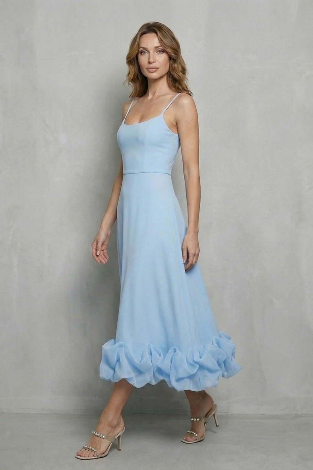 Side profile of a women's elegant light blue midi dress with thin straps and a unique ruffled hem, perfect for a midi dress with sleeves.