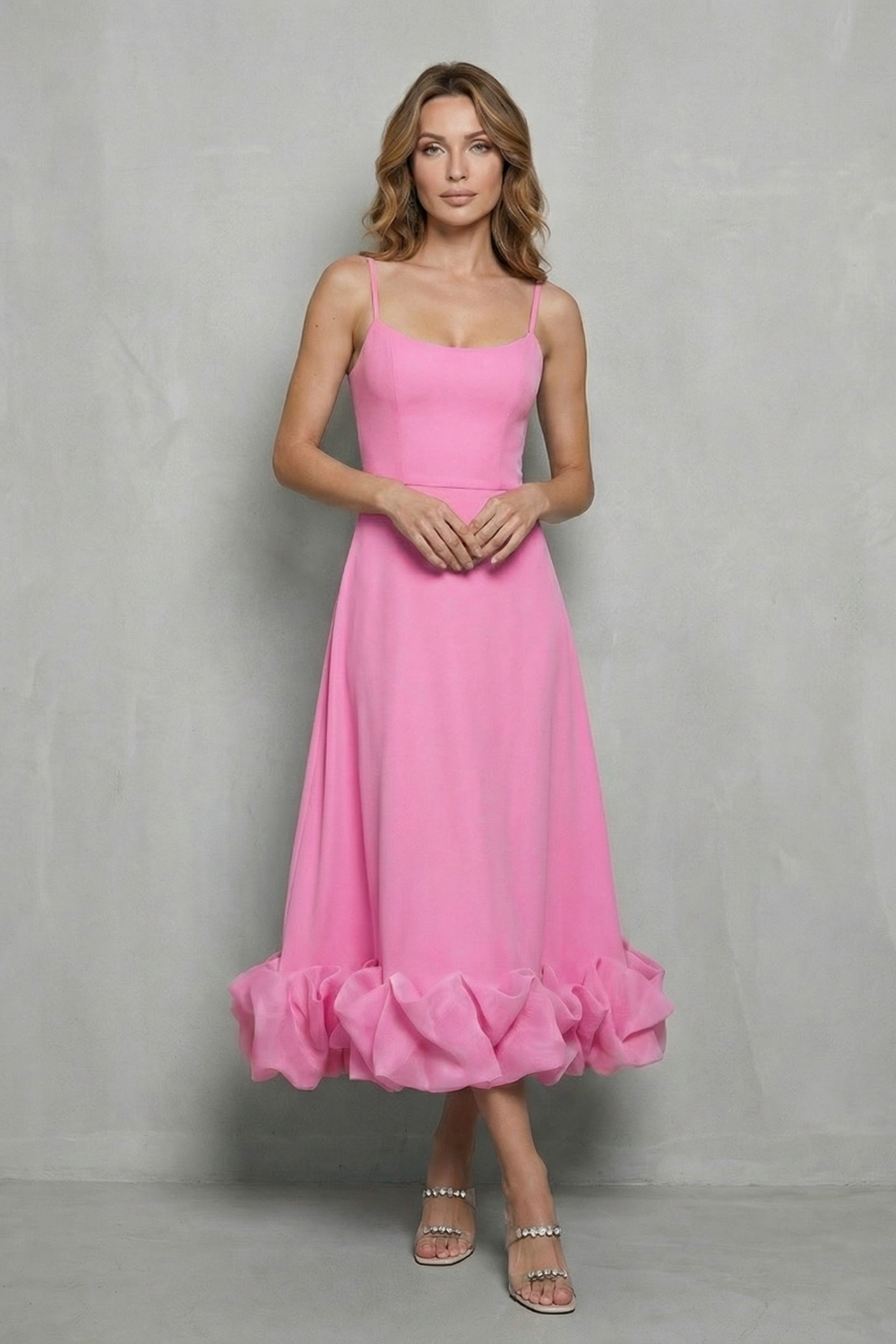 Full-length view of a women's bright pink sleeveless midi dress, designed with spaghetti straps and an eye-catching ruffled hem.