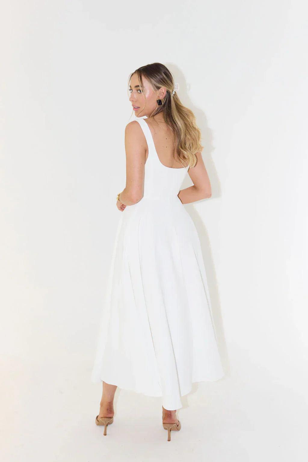 Back view of a white square neck midi dress, showing the elegant cut and movement of the skirt.