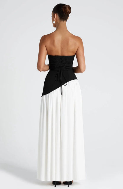 Back view of a women's strapless asymmetric corset maxi dress in black and white, featuring a lace-up corset back.