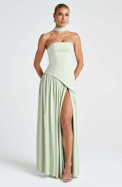 Front view of a women's strapless asymmetric corset maxi dress in light sage green, showcasing a high leg slit and choker detail.