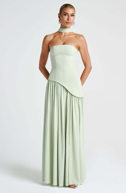 Front view of a women's strapless asymmetric corset maxi dress in light sage green, featuring a subtle asymmetric hem and choker neckline.