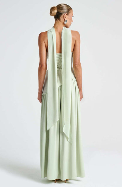 Back view of the light green strapless asymmetric corset maxi dress, featuring a lace-up corset detail and flowing fabric.