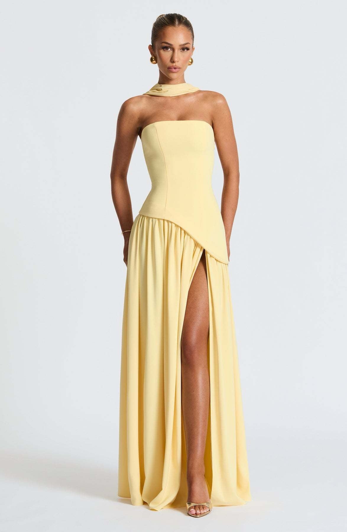 Model posing in the yellow strapless asymmetric corset maxi dress, showcasing the high leg slit and elegant silhouette.