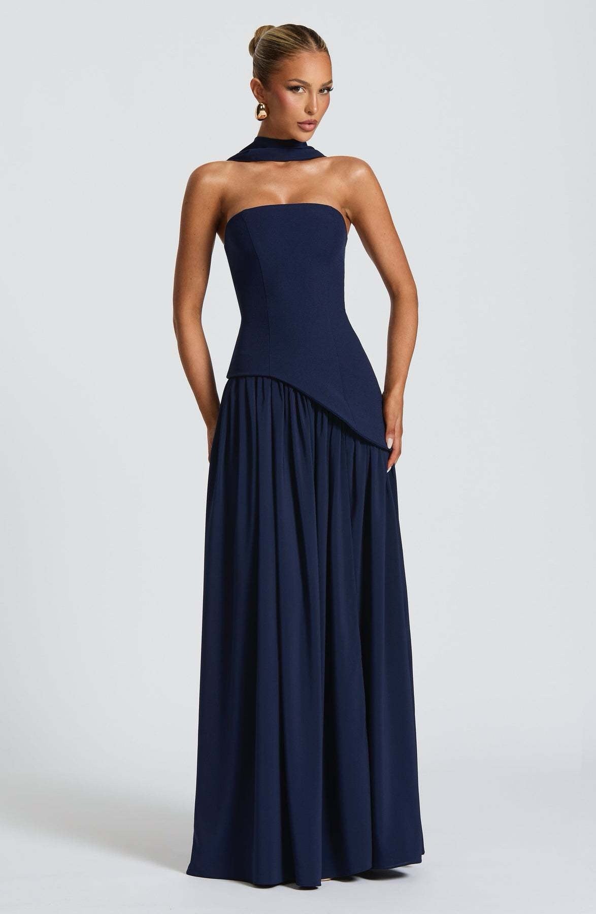Navy blue strapless asymmetric corset maxi dress with a flowing skirt and a matching choker neck scarf.