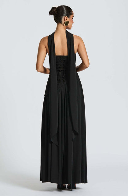 Back view of a black strapless maxi dress with a lace-up corset bodice and a long, elegant scarf drape.