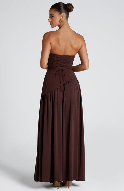 Back view of the brown strapless asymmetric maxi dress, showing the lace-up corset detail on the bodice.
