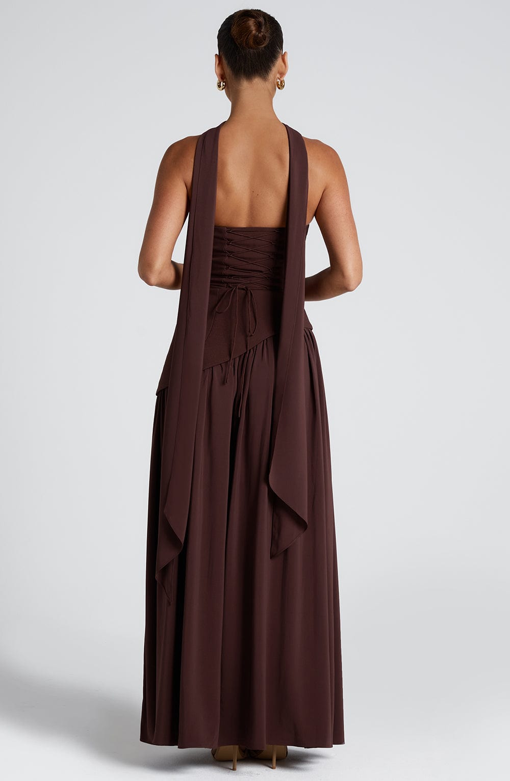 Rear view of the brown strapless maxi dress, featuring the lace-up back and long flowing scarf details.