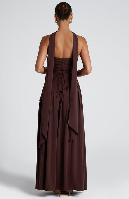 Rear view of the brown strapless maxi dress, featuring the lace-up back and long flowing scarf details.
