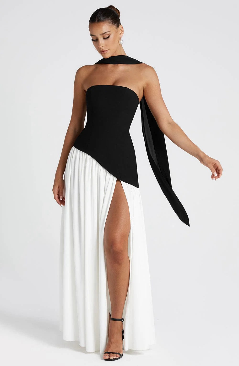 Black and white strapless asymmetric corset maxi dress with a high slit, front view, elegant and modern.