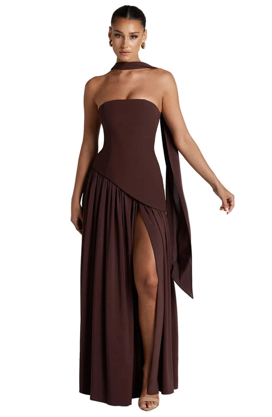 Brown strapless asymmetric corset maxi dress with a high slit and flowing scarf detail, front view.
