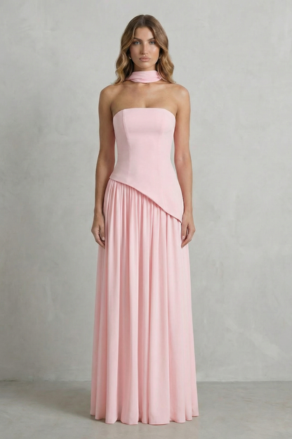 Soft pink strapless asymmetric maxi dress, featuring a fitted bodice and a full, elegant pleated skirt, suitable for wedding guests.