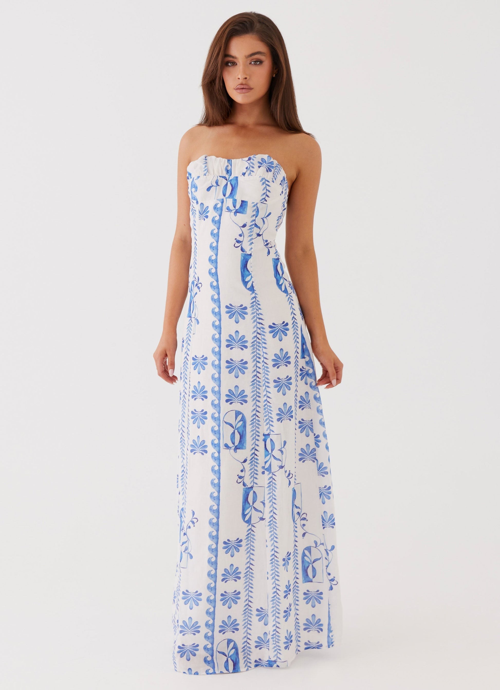Women's strapless A-line maxi dress in white with blue floral and leaf patterns, front view.