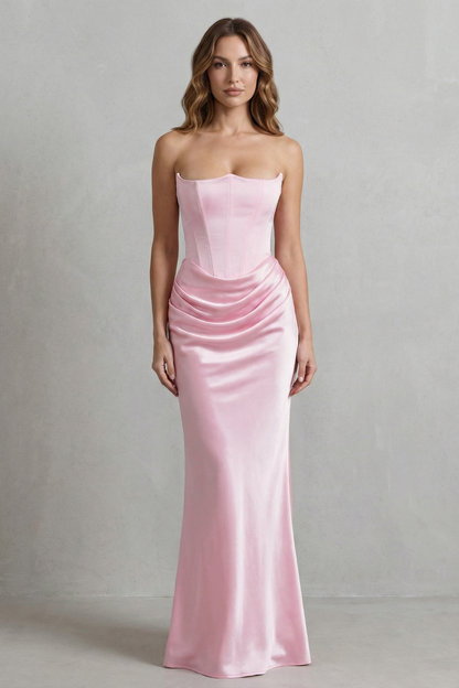 Front view of a woman wearing a light pink strapless satin maxi dress, featuring a corset top and elegant draped waist.