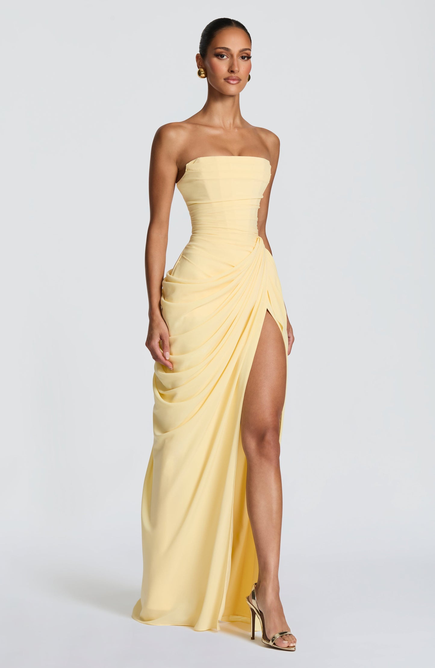 Side profile of the light yellow strapless dress, highlighting the thigh-high split and flowing draped skirt, perfect for vacation dresses.