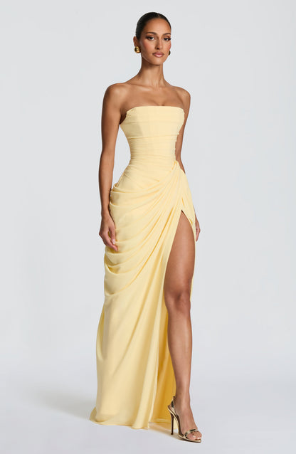 Side profile of the light yellow strapless dress, highlighting the thigh-high split and flowing draped skirt, perfect for vacation dresses.