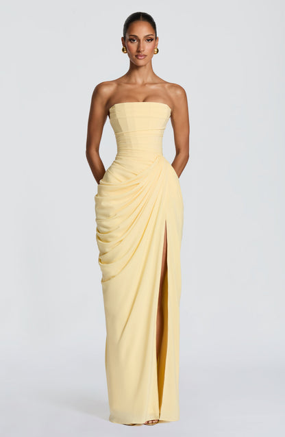 Full front view of the elegant light yellow strapless corset maxi dress, featuring a flattering draped design and high leg split.
