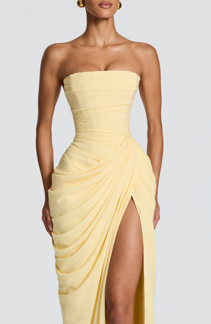 Close-up front view of the light yellow strapless maxi dress, showing the detailed corset bodice and draped split skirt.