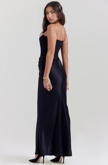 Back view of a woman wearing a black strapless corset maxi dress, showing the sleek lines and subtle train.