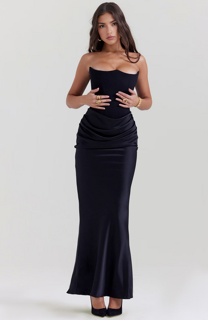Front view of a black strapless corset maxi dress, emphasizing the fitted bodice and flowing skirt with ruched detail.