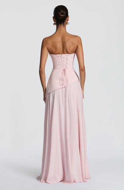 Back view of a light pink strapless cowl neck maxi dress with a lace-up corset back and flowing skirt.