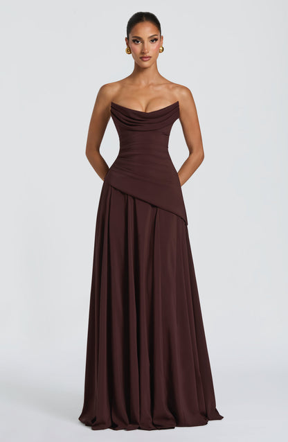 Front view of a dark brown strapless cowl neck maxi dress with a fitted bodice and pleated skirt.