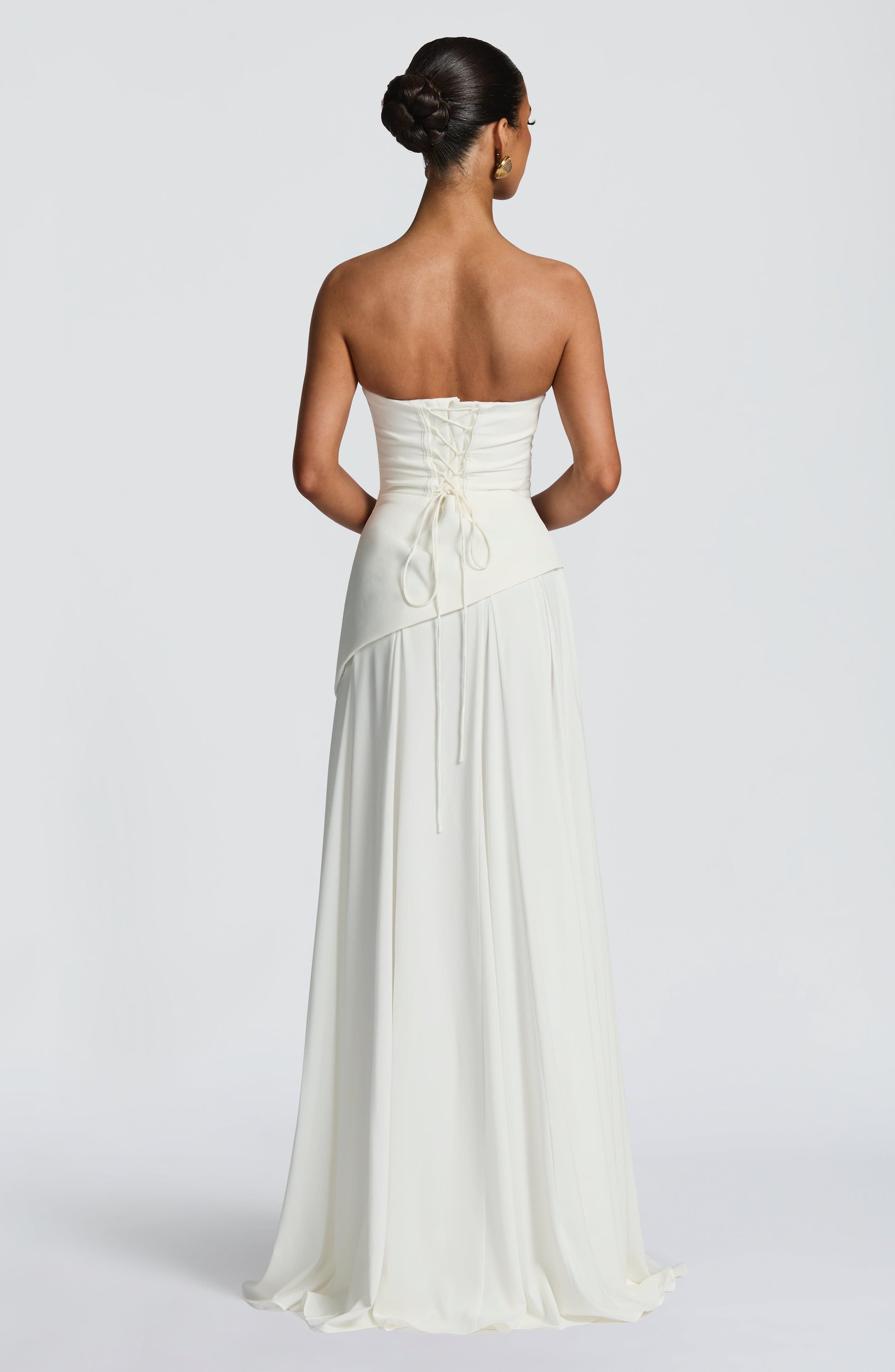 Rear view of the white strapless maxi dress, showing the elegant lace-up back closure and flowing skirt.