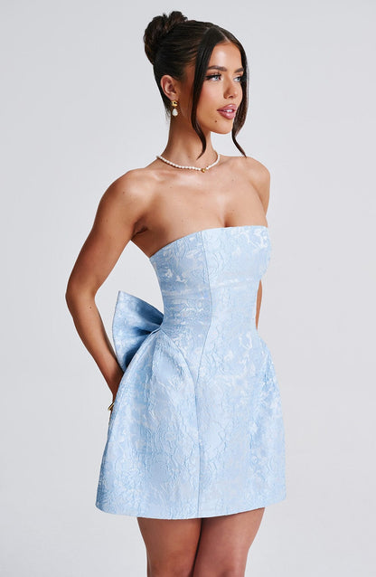 Side profile of a women's light blue strapless floral bow mini dress, showing the subtle bow at the back.