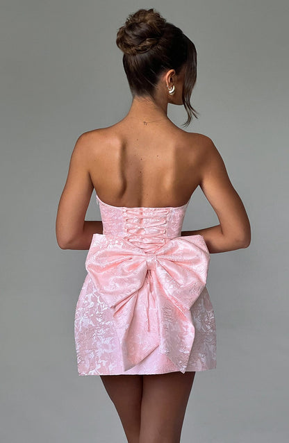 Back view of the light pink strapless floral mini dress, showcasing a large bow detail and corset-style lacing.