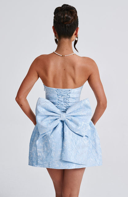 Back view of a light blue strapless mini dress with a large bow detail and corset lacing.