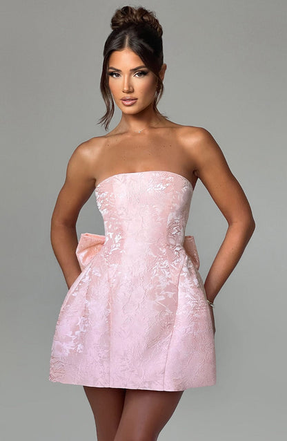 Front view of the women's light pink strapless floral mini dress, with the model standing against a grey background.