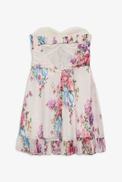 Back flat lay of a white strapless floral mini dress with an open back, showcasing the pink, purple, and blue flower print and ruffled bottom edge.