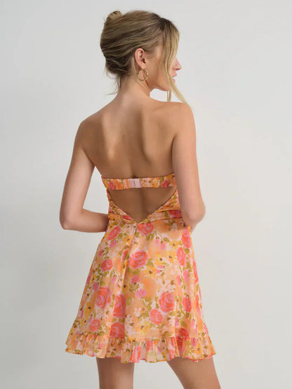 Back view of a women's strapless mini dress in a vibrant orange and pink floral print, showcasing the open-back design and ruffled hem.