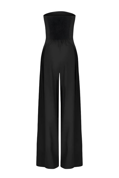Back view of a black strapless high-waisted wide-leg jumpsuit for women, highlighting the smocked bodice and flowing pant legs on a white background.