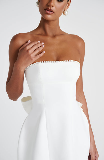 Close-up of the bodice of the white strapless mini dress, detailing the pearl embellishments and structured fit.