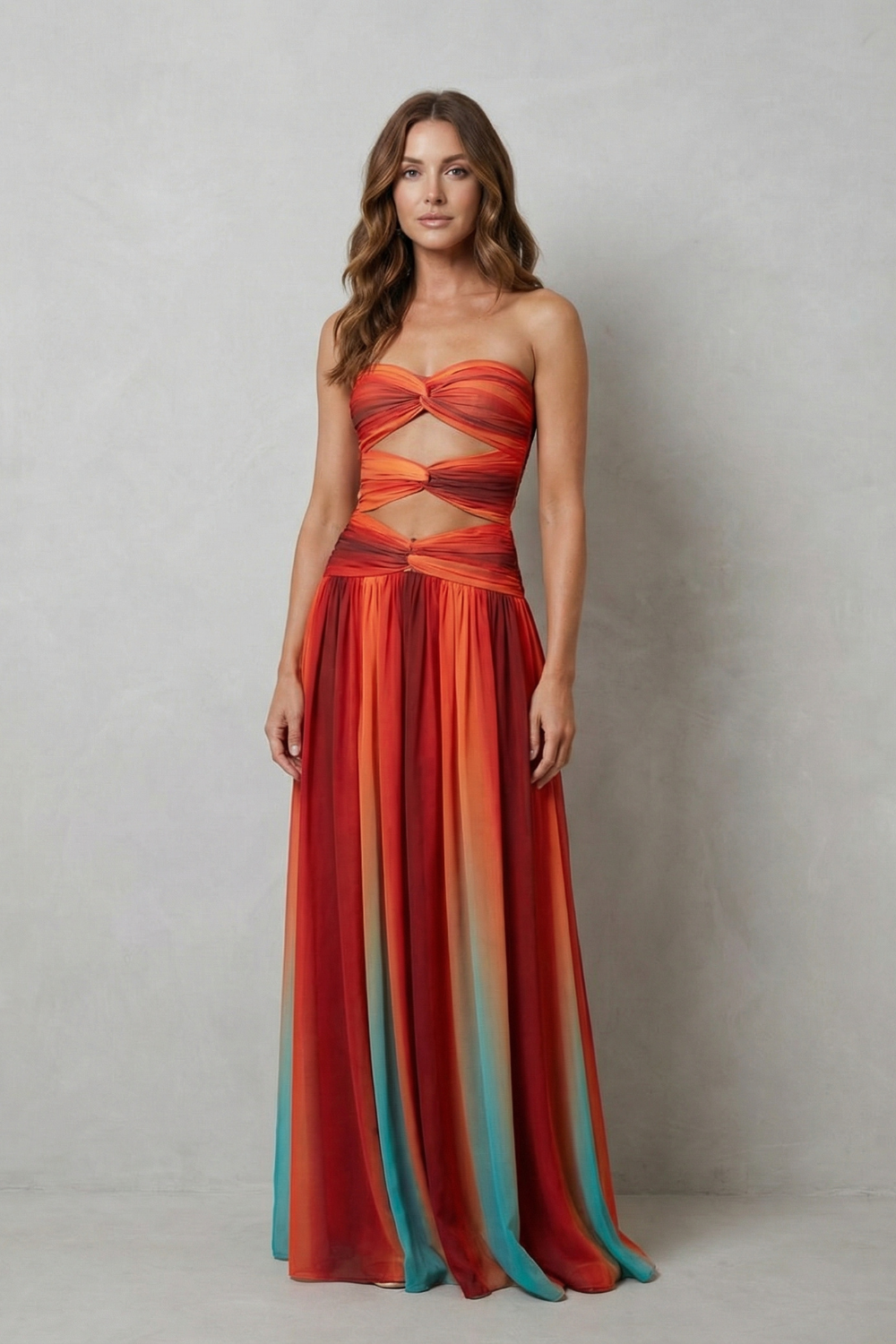 Women's elegant strapless ombre maxi dress with twisted bust detail and waist cut-outs, featuring vibrant orange and red hues.