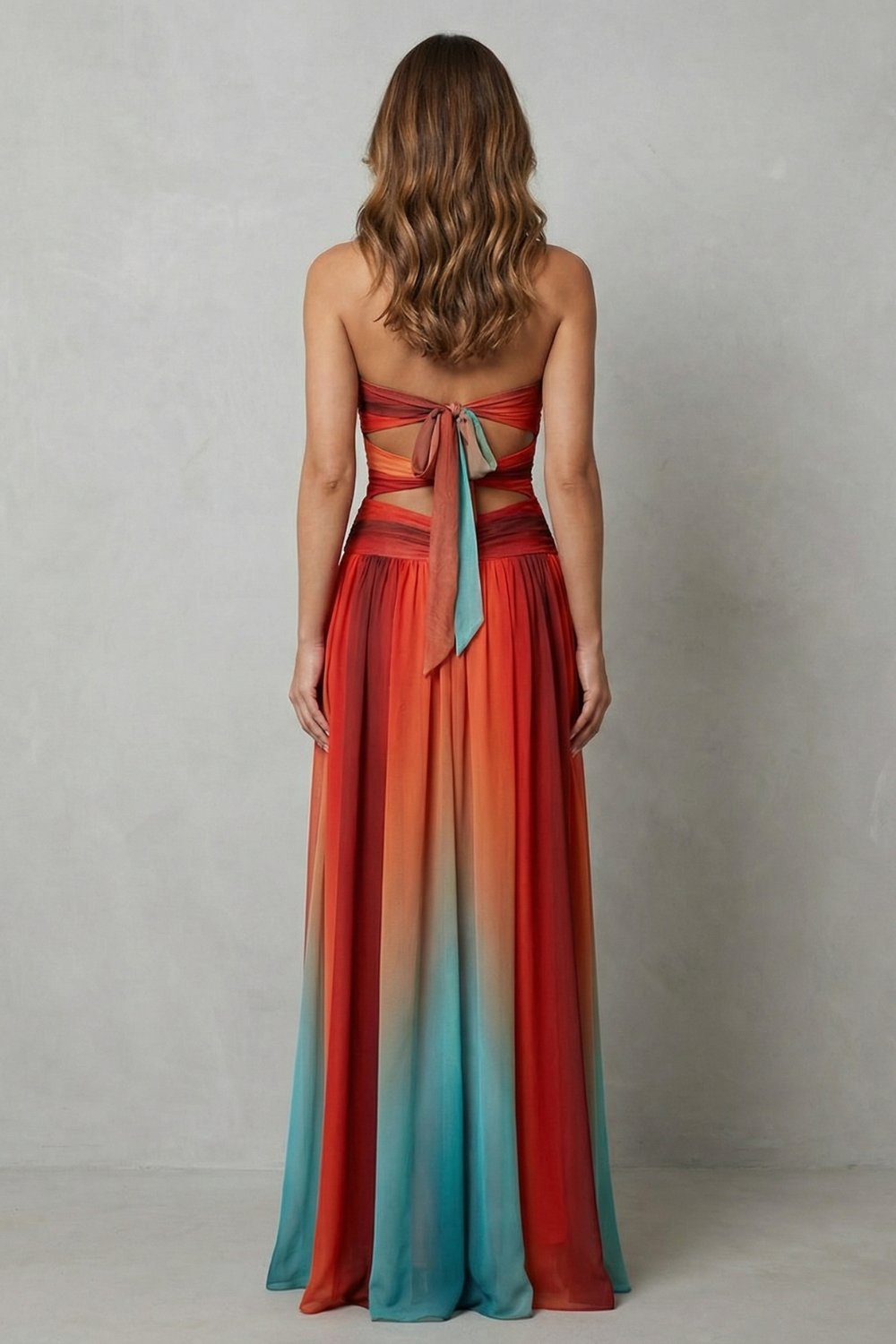 Back view of a women's strapless ombre maxi dress with a tie-back closure and waist cut-outs, in rich orange and red tones.